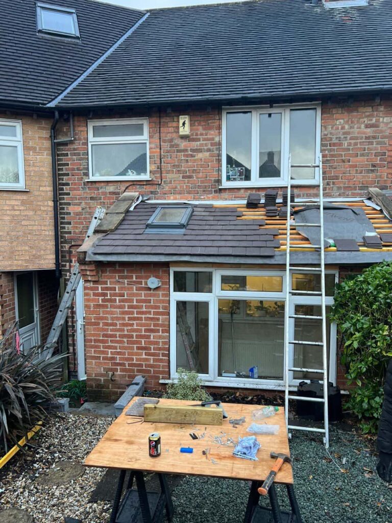 This is a photo of a roof extension that is having new roof tiles installed. This is a photo taken from the roof ridge looking down a tiled pitched roof on to a flat roof. Works carried out by Chichester Roofing Repairs