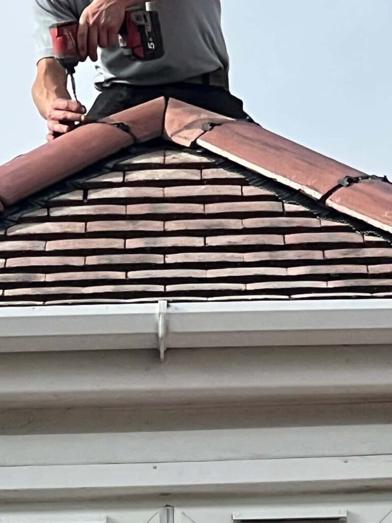 This is a photo of one of the operatives of Chichester Roofing Repairs installing new ridge tiles