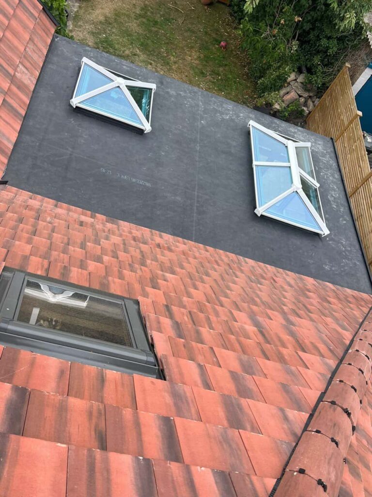 This is a photo taken from the roof ridge looking down a tiled pitched roof on to a flat roof. Works carried out by Chichester Roofing Repairs